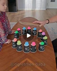 a child is sitting at a table with chalk markers on it and an adult holds out their hand