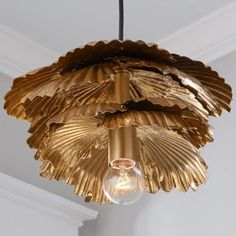 a light fixture made out of gold leaf material hanging from a ceiling in a room