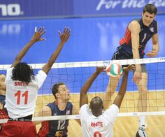 the men are playing volleyball on the court