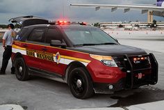 a red police car parked in front of an airplane