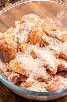 a bowl filled with meat covered in powdered sugar on top of a wooden table