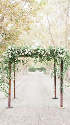 an outdoor ceremony with greenery and white flowers