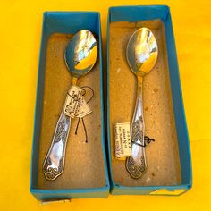 two spoons are in a box on a yellow tablecloth and one is empty