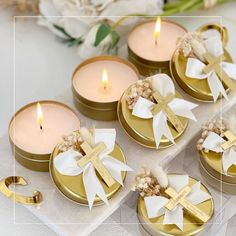 four small candles with bows on them sitting next to some flowers and other things in the background