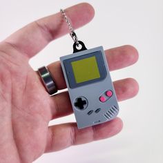 a hand holding a gameboy keychain that is attached to a chain