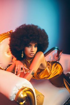 a woman with an afro is laying on a bed and posing for the camera in front of a mirror