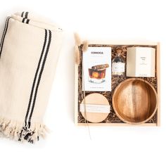 a wooden bowl and spoon in a box next to a white towel with black stripes