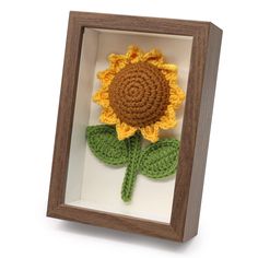 a crocheted sunflower in a wooden frame