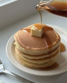 a stack of pancakes with syrup being drizzled on top