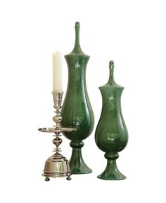 two green vases sitting next to each other with a candle on top of them