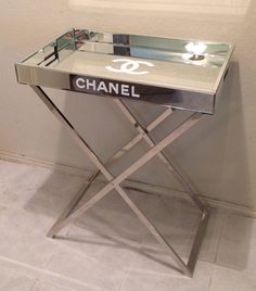 a mirrored table with the word chanel on it in front of a white wall