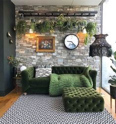 a living room with green couches and plants hanging on the brick wall behind it