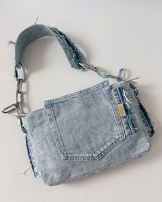 an old jean purse with chains hanging from it's front and side pockets, on a white surface