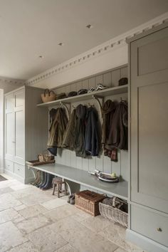 a coat rack filled with lots of coats and shoes next to a bench in a room