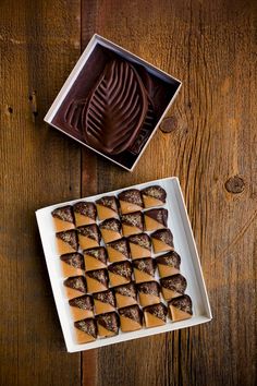 a box of chocolate covered desserts sitting on top of a wooden table next to a container