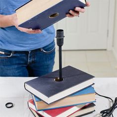 a person is holding a book while standing on top of a stack of books with a microphone attached to it