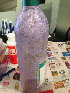 a purple vase sitting on top of a table next to some pens and glues