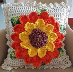 a crocheted sunflower pillow sitting on a chair in front of a window