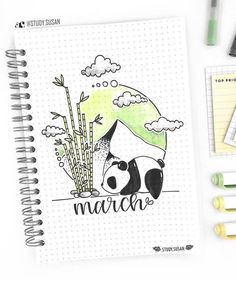 a notebook with an image of a panda bear and bamboos on it, surrounded by markers