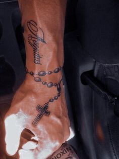 a person with a rosary tattoo on their arm and wrist is sitting in a car