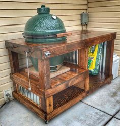 a big green egg sitting on top of a wooden stand next to a building with a door