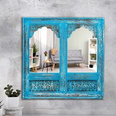 an ornate blue mirror on the wall above a table with a potted plant in front of it