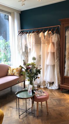 a room filled with lots of wedding dresses hanging on the rack next to a window