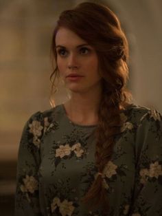 a woman with long hair wearing a flowered dress and braid in front of her face