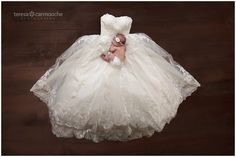 a baby in a white dress laying on top of a wooden floor