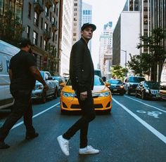 two men walking down the street in front of cars