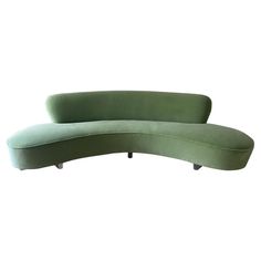 a green curved couch sitting on top of a white floor