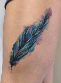 a watercolor feather tattoo on the thigh