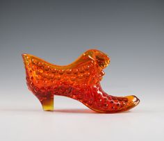 an orange glass shoe sitting on top of a table