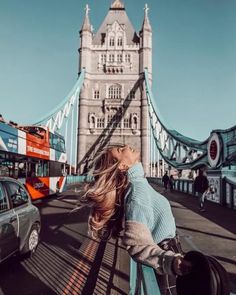 a woman standing in front of the tower bridge with her hair blowing in the wind