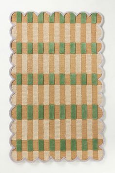 a brown and green checkered rug with scalloped edges on a white background