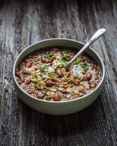 a bowl of beans and rice soup with a spoon in it on a wooden table