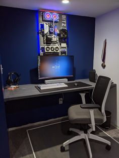 a room with a desk, chair and computer monitor on the wall in front of it