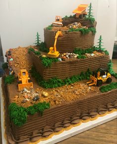 a three tiered cake is decorated with construction equipment and dirt on the bottom layer