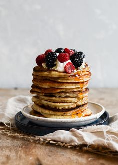 a stack of pancakes topped with berries and syrup