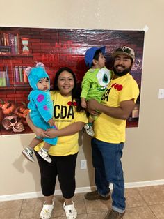 two adults and one child standing in front of a poster