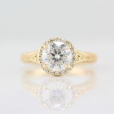 a yellow gold engagement ring with an oval cut diamond surrounded by small round brilliant diamonds