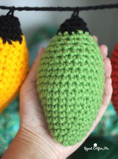 three crocheted fruits are hanging on a line, one is orange and the other is green