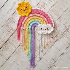 a crocheted rainbow with a smiling face on the side and tassels attached to it