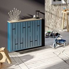 a blue cabinet sitting on top of a wooden floor next to a child's tricycle