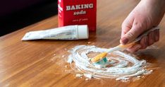 a person is spreading icing on a wooden table next to baking soda and toothpaste