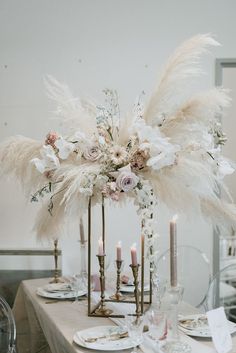 the centerpiece is adorned with feathers, flowers and candles for an elegant touch to the table