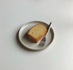 a piece of bread on a white plate with a fork and knife next to it