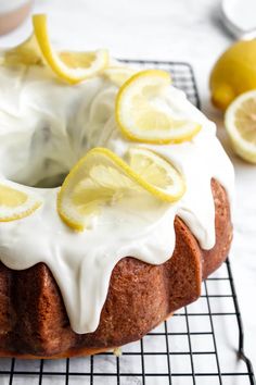 a lemon bunt cake with icing and sliced lemons on a cooling rack