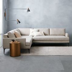 a living room with a couch, table and lamp on the wall next to it