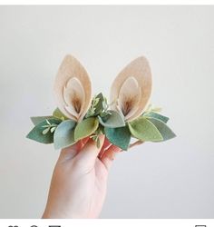 a hand is holding some paper flowers with leaves